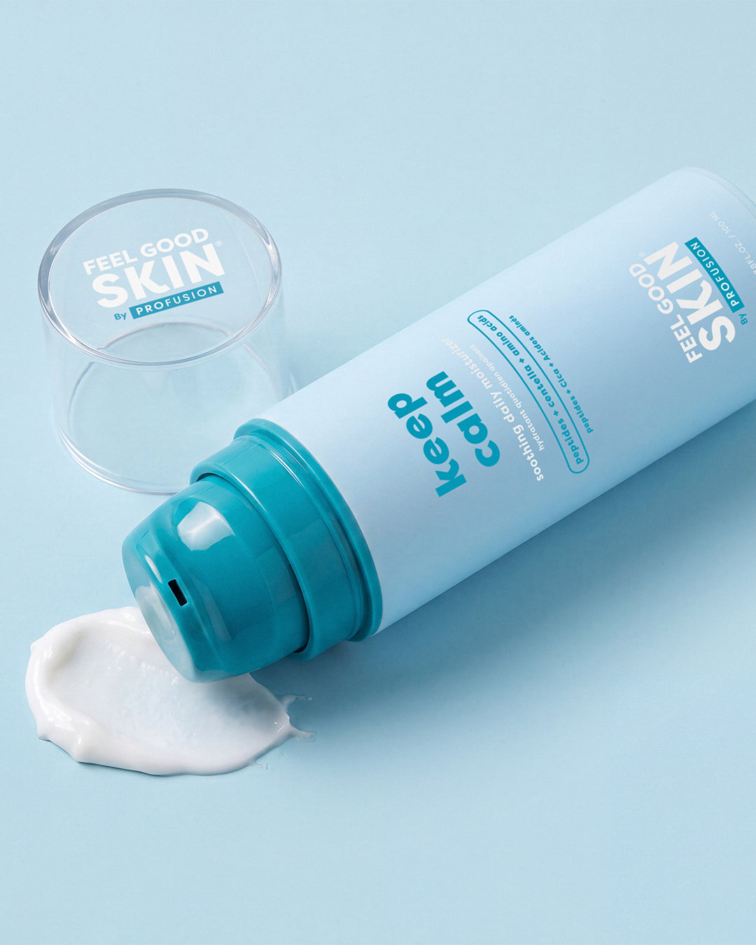 A light blue cosmetic tube labeled 'Keep calm' and 'FEEL GOOD SKIN by PROFESSION' lies on its side with a teal pump, spilling a dollop of white cream on a pale blue background. A clear cap and a small round clear container are placed beside it.