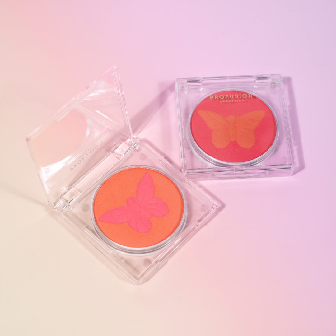 Bright pink and orange blushes from Profusion Cosmetics feature butterfly imprints, showcasing vibrant colors for a bold makeup look.