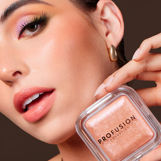 A hand holding the Profusion Cosmetics Holo Beam Holographic Highlighter, emphasizing its radiant peach shade.