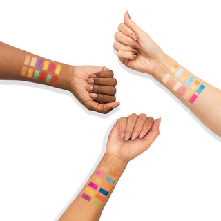 Arm swatches of the vibrant Profusion Cosmetics Kaleidoscope eyeshadow palette, featuring a range of colors from bold reds and blues to soft pinks and golds.