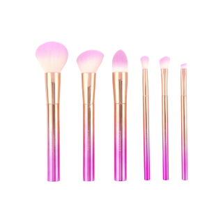 Six-piece makeup brush set with metallic pink and gold ombre handles and pink-tipped bristles.