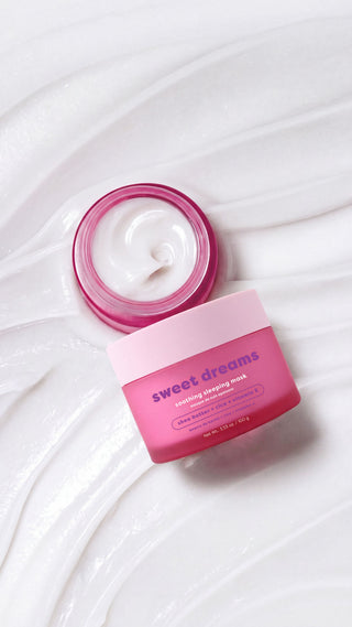 A pink cosmetic jar labeled 'sweet dreams' with its lid off, showing white cream inside, set on a white background with decorative cream swirls.