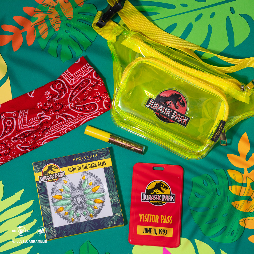 colorful leaves and teal backdrop, with headband and glow in the dark gem next to chrome liner and a bage that say &quot; visitor pass&quot; with the bag above them 