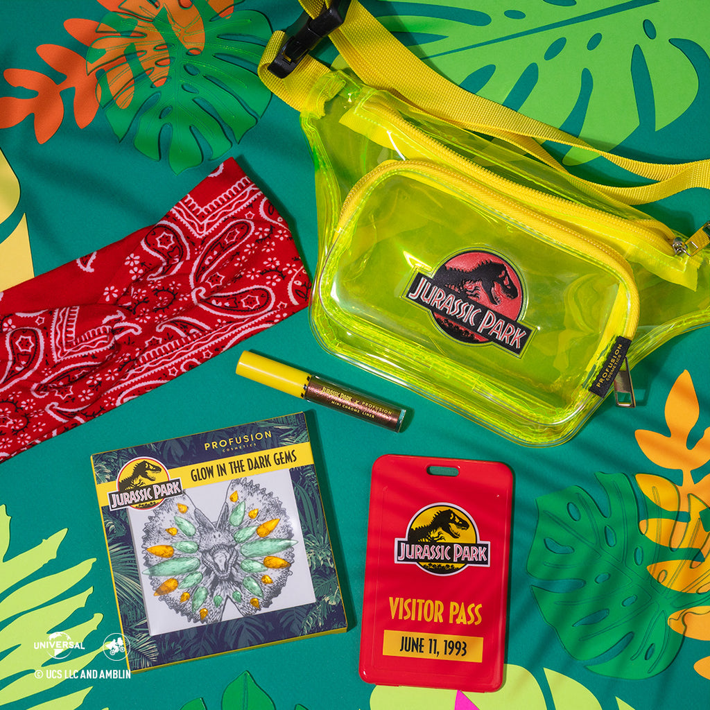 colorful leaves and teal backdrop, with headband and glow in the dark gem next to chrome liner and a bage that say " visitor pass" with the bag above them 