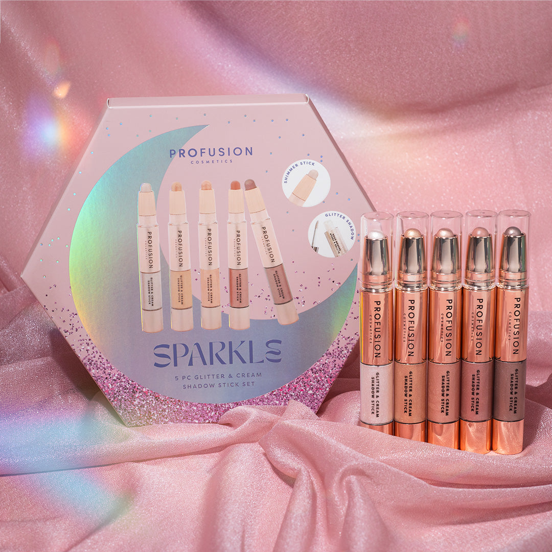 Hexagonal box of Profusion Cosmetics Sparkles Shadow Stick Set with five glitter and cream sticks on pink fabric.